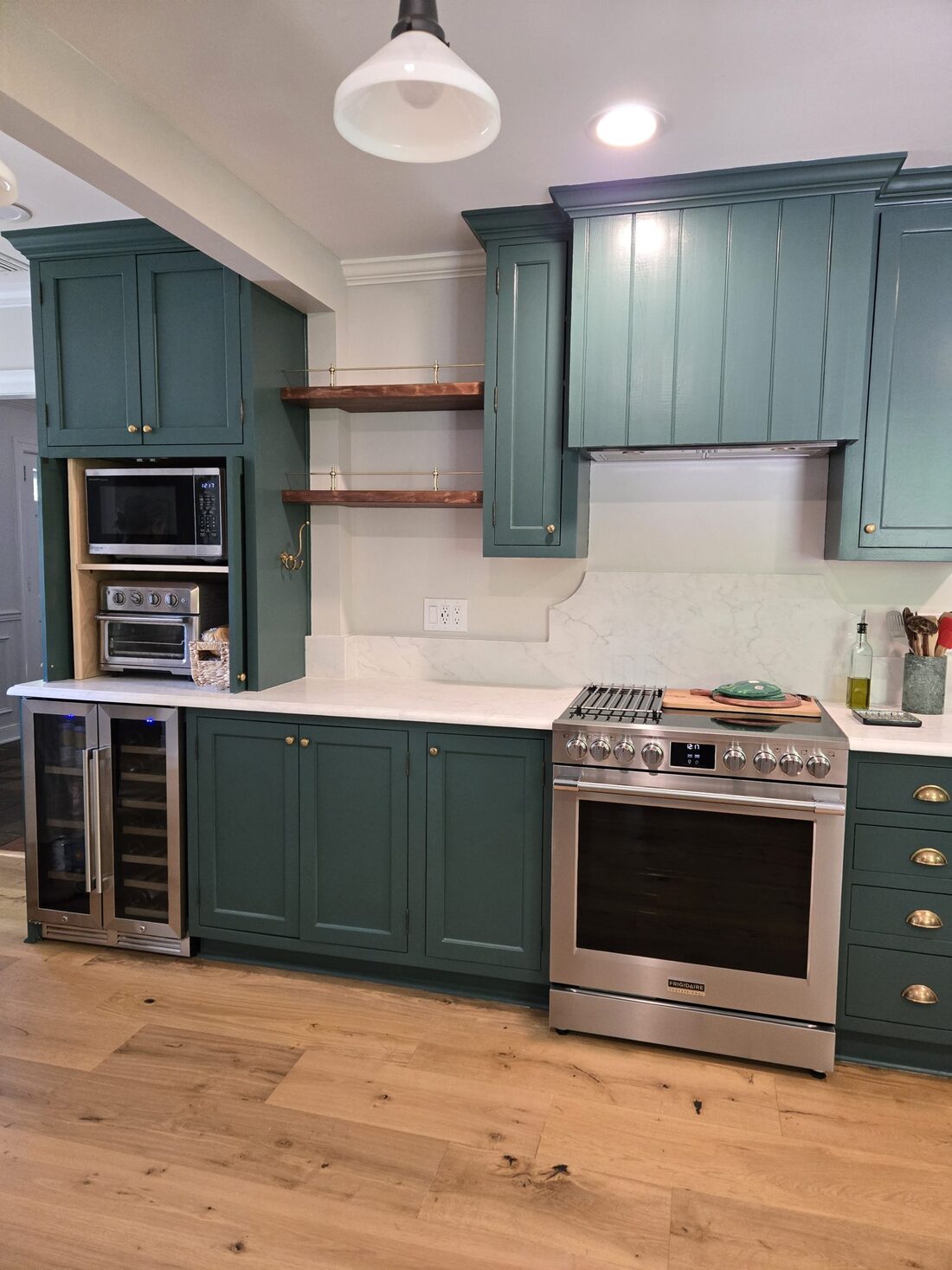 Hunter-green inset kitchen with brass hardware and white-oak floors, built by Hochstoeger & Vega