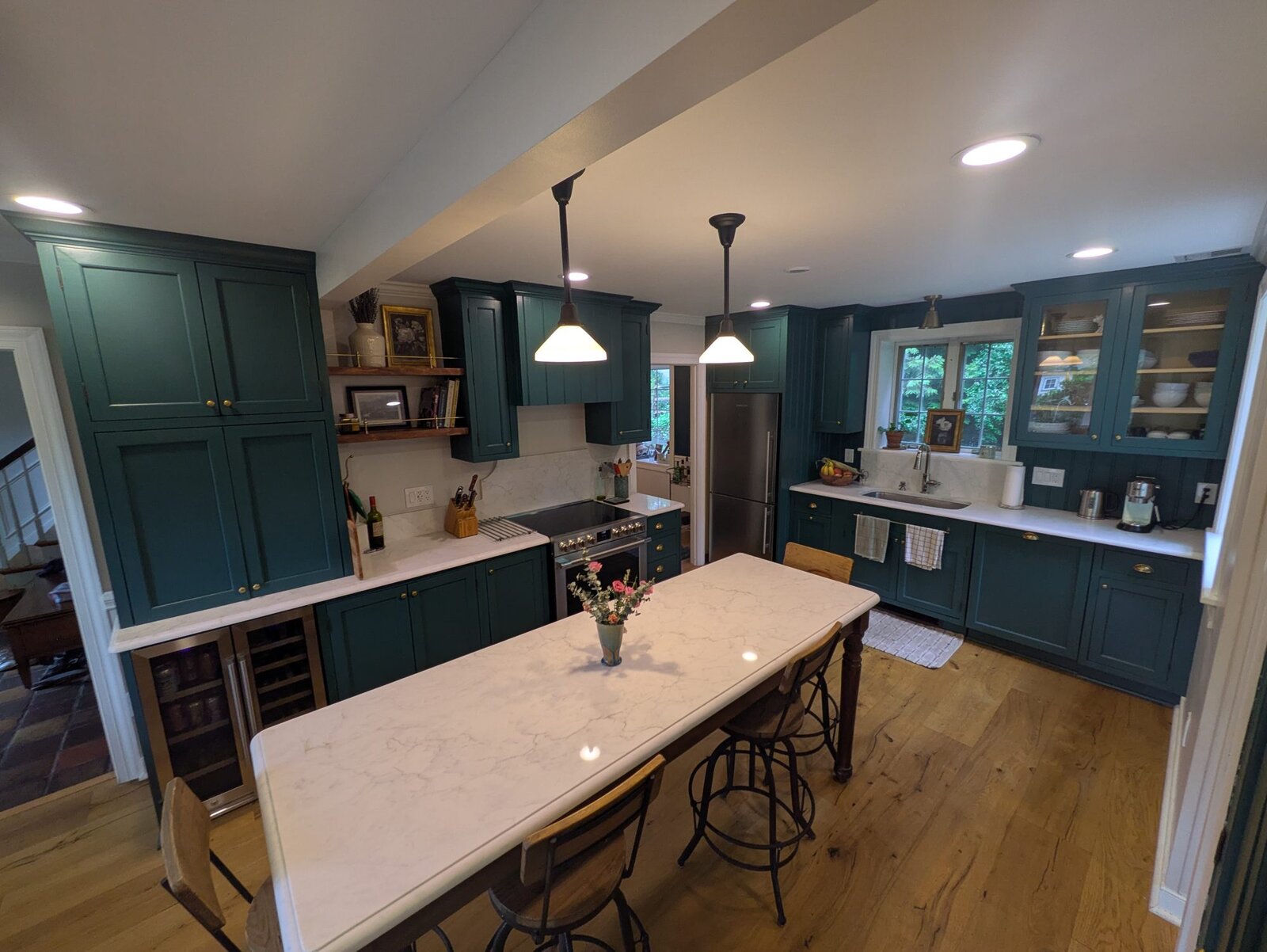 Hunter-green kitchen with a large island, brass hardware and white-oak floors